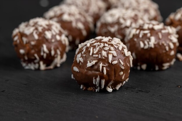 Foto schokoladenbonbons in form von kugeln mit milchkokosfüllung, bestreut mit kokosnussstückchen, köstliche und weiche schokoladen-kokoskuchen in kleiner größe