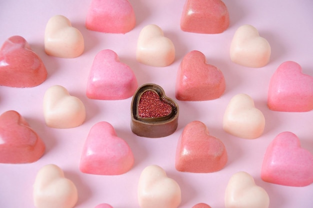 Schokoladenbonbons in Form von rosa Herzen Rosa einfarbiger Hintergrund