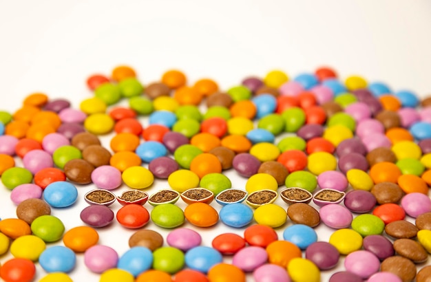 Schokoladenbonbons in verschiedenen Farben auf weißem Hintergrund Die Bonbons werden halbiert Schädliche Babynahrung