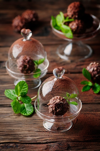 Foto schokoladenbonbons mit nüssen, minze und kakao auf dem vintage-tisch