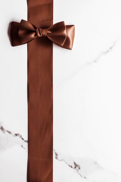 Schokoladenbraunes Seidenband auf Marmorhintergrund flachgelegt