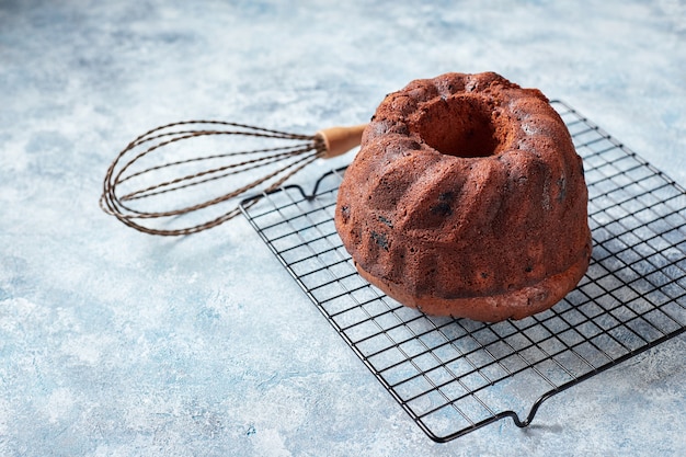 Schokoladenbundt-Kuchen auf einem Metalldrahtgestell, Puderzucker und Preiselbeeren in Schalen, für die Dekoration vorbereitet