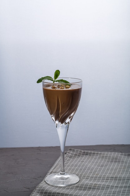 Schokoladencocktail mit Nüssen und Minze in einem Glas auf schwarzem Hintergrund. Vertikales Foto