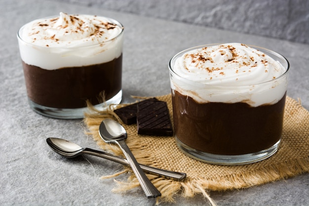 Schokoladencreme mit Sahne im Glas auf Grau