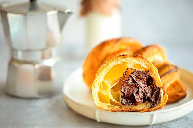 Schokoladencroissant. Croissant mit Schokoladenfüllung. Geschnittenes Croissant mit Schokolade. Leckeres Dessert zum Frühstück. Frühstück in einem Café. Süßes Frühstück mit Kaffee