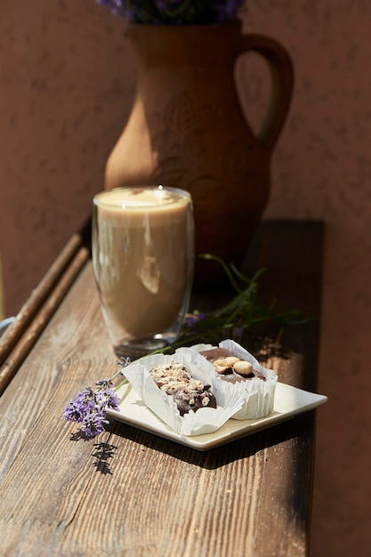 Schokoladendessert mit Glas Latte und Lavendelblüten draußen auf der Caféterrasse Sommerfrühstück Kaffeezeit Harte Schatten