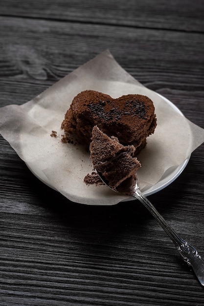 Schokoladendessertkeks in Form eines Herzens liegt auf einem hölzernen Hintergrund