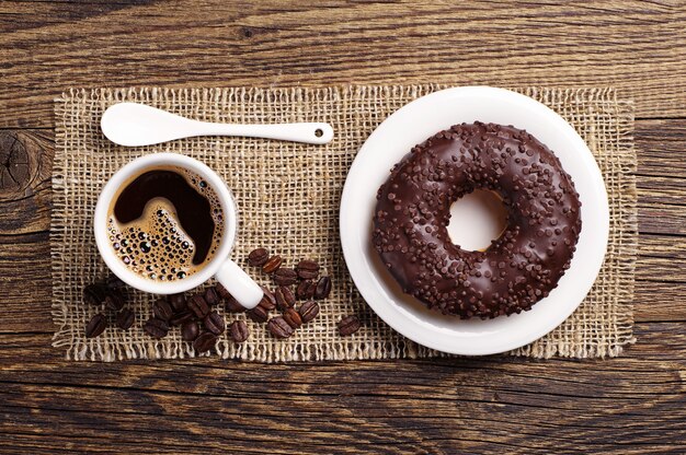 Schokoladendonut und Tasse Kaffee auf Holztisch, Draufsicht