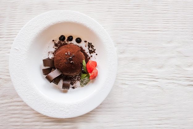 Schokoladenfondant mit Dekoration aus Erdbeere und Minze auf Holztisch Köstliches Dessert serviert in der Draufsicht des Restaurants mit freiem Platz