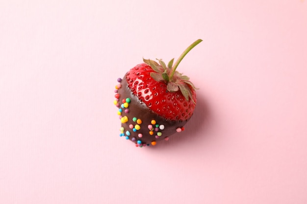 Schokoladenfondue. Erdbeere in der Schokolade auf rosa Hintergrund