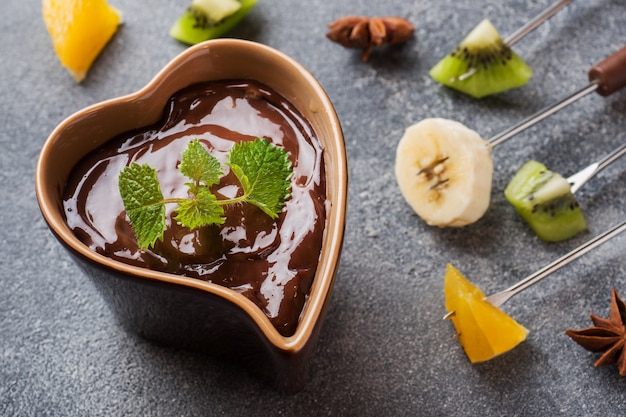 Schokoladenfondue mit Früchten auf dunklem Beton