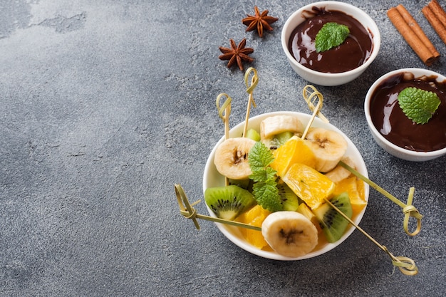 Schokoladenfondue mit Früchten auf dunklem Beton