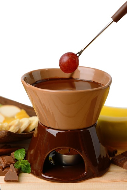 Schokoladenfondue mit Früchten auf Holztisch auf hellem Hintergrund