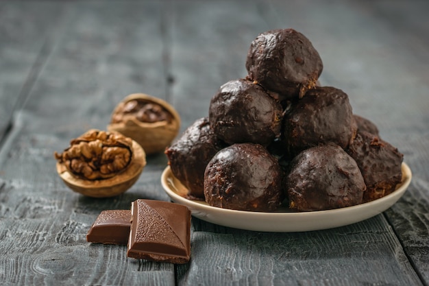 Schokoladengetränkte Kugeln aus geriebenen Nüssen und getrockneten Früchten in einer Schüssel auf einem Holztisch. Leckere frische hausgemachte Süßigkeiten.