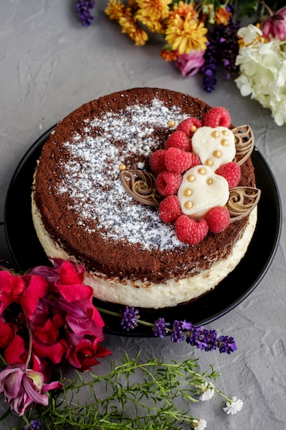 Schokoladenhimbeercremekuchen mit Blumen auf einem grauen Hintergrund