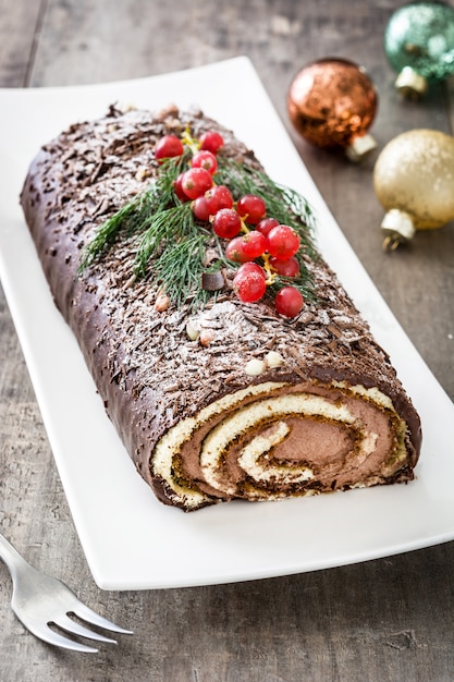 Schokoladenjulblock-Weihnachtskuchen mit roter Johannisbeere auf hölzernem.