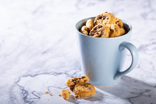 Schokoladenkekse in der blauen Tasse auf Marmorsteinoberfläche. Selektiver Fokus. Speicherplatz kopieren