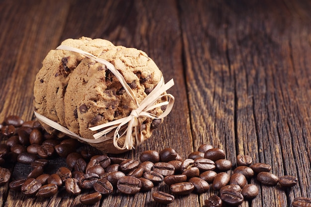 Schokoladenkekse mit einem Band und Kaffeebohnen auf dunklem Holztisch gebunden