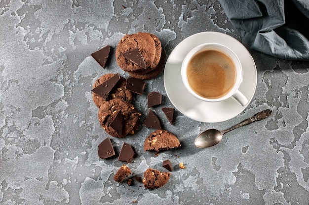 Schokoladenkekse und ein Tasse Kaffee auf einem grauen konkreten Hintergrund. Ansicht von oben