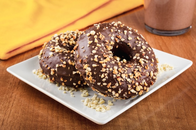 Schokoladenkrapfen bedeckt mit Mandelstücken auf einem Holztisch