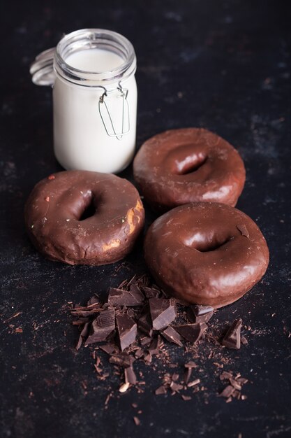 Schokoladenkrapfen in der Nähe einer Flasche Milch und Schokoladenkrümel. Süßer Snack.