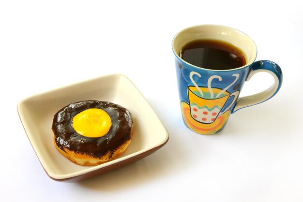 Schokoladenkrapfen mit buntem Tasse Kaffee lokalisiert auf weißem Hintergrund