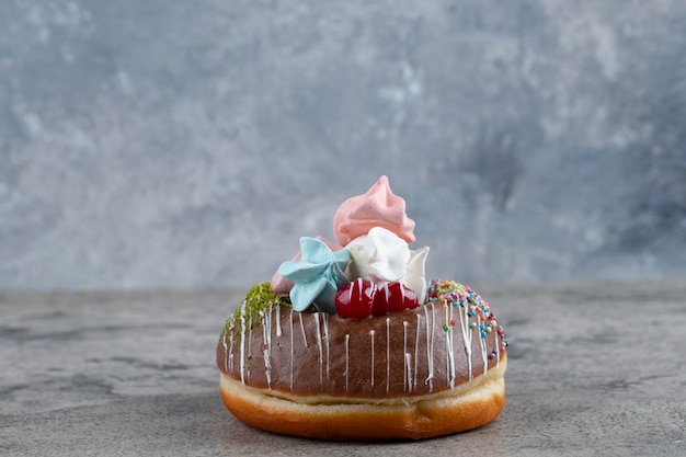 Schokoladenkrapfen mit bunten Baisersüßigkeiten auf Steinhintergrund.