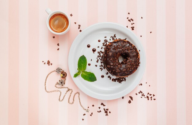 Schokoladenkrapfen mit einem Minzblatt auf einem Teller nahe einer Tasse Kaffee