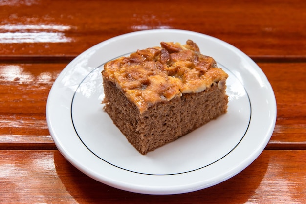 Schokoladenkuchen auf einem weißen Teller sieht auf einem Holztisch appetitlich aus