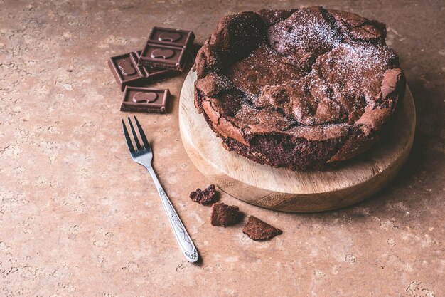Schokoladenkuchen auf hölzernem Behälter mit Gabel.