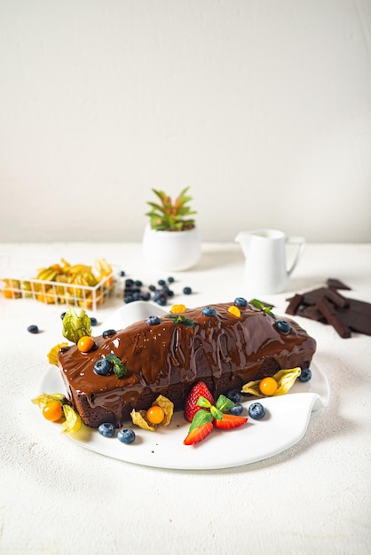 Schokoladenkuchen mit Beeren auf einem weißen Hintergrund, der selektiven Fokus tönt