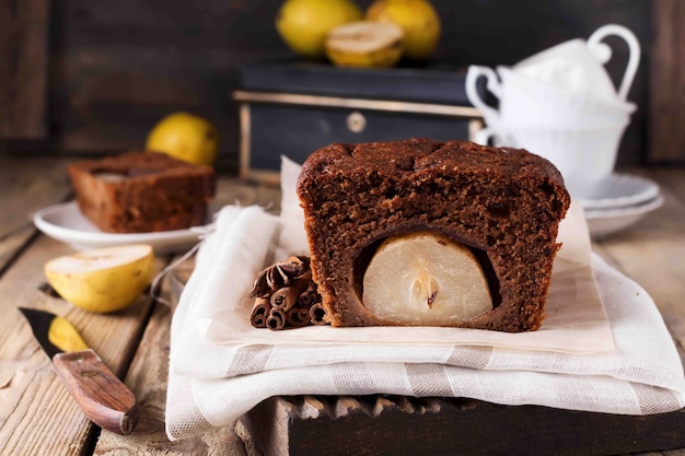 Schokoladenkuchen mit Birnen und Zimt auf altem Holzhintergrund