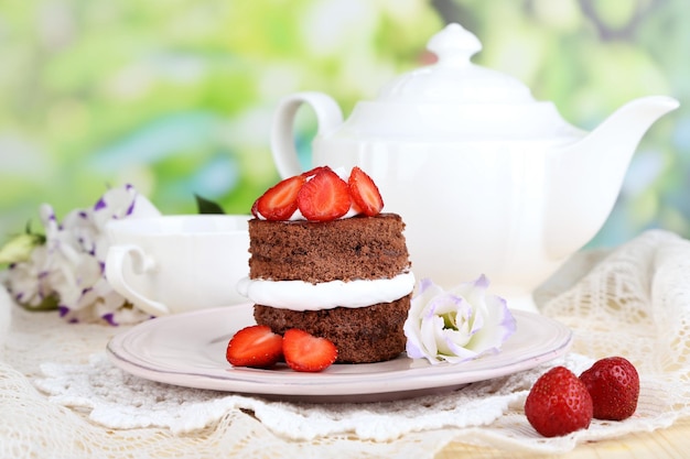 Schokoladenkuchen mit Erdbeeren auf Holztisch auf natürlichem Hintergrund