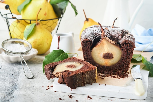 Schokoladenkuchen mit innen gebackenen Birnen Schokoladen-Birnen-Kuchen oder dunkler Schokoladen-Bundt-Kuchen mit Birne auf hellgrauem Tisch zu Hause Konzept für Hausmannskost und Backrezepte Selektiver Fokus