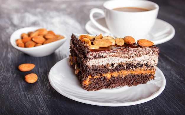 Schokoladenkuchen mit Karamell, Erdnüssen und Mandeln auf einer schwarzen Holzoberfläche.