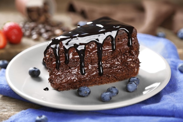 Schokoladenkuchen mit Schokoladencreme und frischen Heidelbeeren auf Teller auf Holzhintergrund