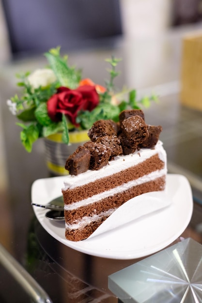 Schokoladenkuchen und weiße Sahne mit Blumentopf auf dem Tisch