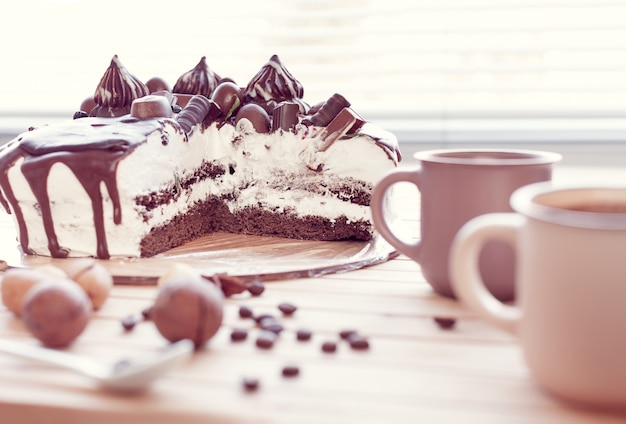 Foto schokoladenkuchen verziert mit pralinen mit macadamianüssen und zwei tassen kaffee