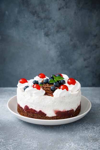 Schokoladenkuchen, weißer Käsekuchen, dekoriert mit Heidelbeeren, kirschbrauner Schokolade und Schlagsahne
