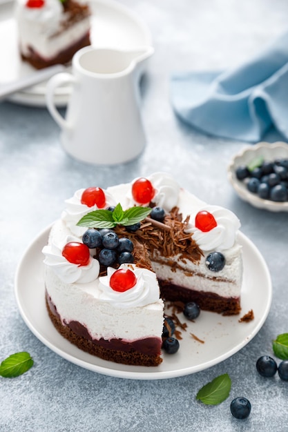 Schokoladenkuchen, weißer Käsekuchen, dekoriert mit Heidelbeeren, kirschbrauner Schokolade und Schlagsahne