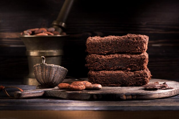 Schokoladenkuchenstücke aus dunkler Schokolade und Bio-Kakaobohnen auf dunklem rustikalem Hintergrund