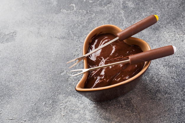 Schokoladenmasse mit Zimt und Anis. Fondue mit Schokolade auf einer dunklen konkreten Tabelle.