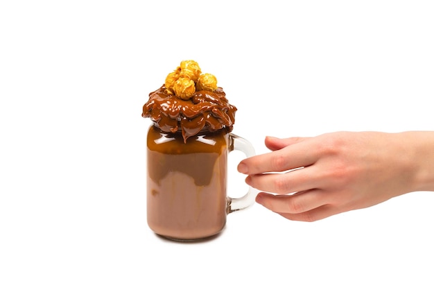 Schokoladenmilchshake mit Schlagsahne, Keksen, Waffeln, serviert im Einmachglas. "In der Hand der Frau isoliert. Platz für Text oder Design.