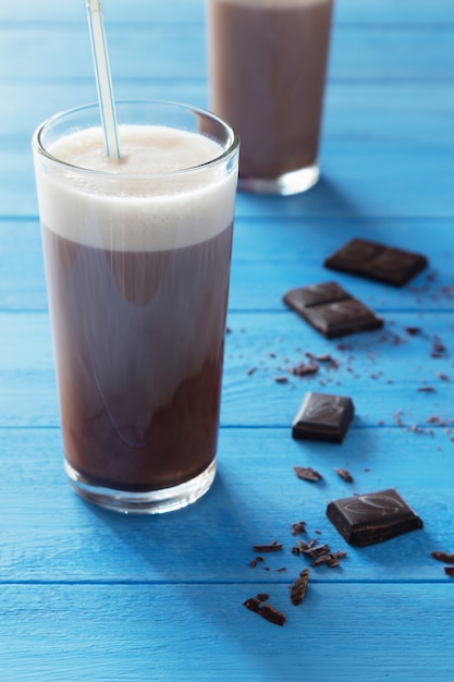 Schokoladenmilchshake und Schokoladenkrumen auf blauem hölzernem Hintergrund