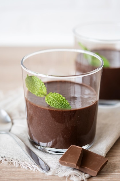 Schokoladenmousse-Dessert, garniert mit Minzblatt auf einem Holztisch