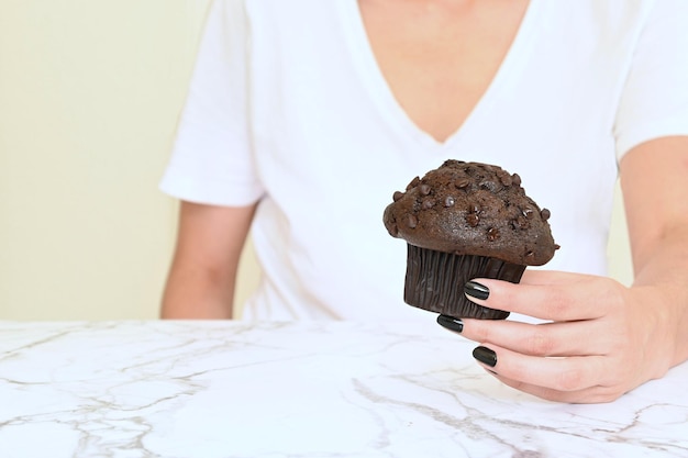 Schokoladenmuffin, gehalten von einer Frauenhand auf weißem Hintergrund