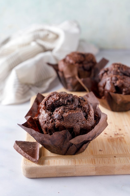 Schokoladenmuffin mit Papiereinschlag und einer Unze Schokolade auf einem Holzsockel