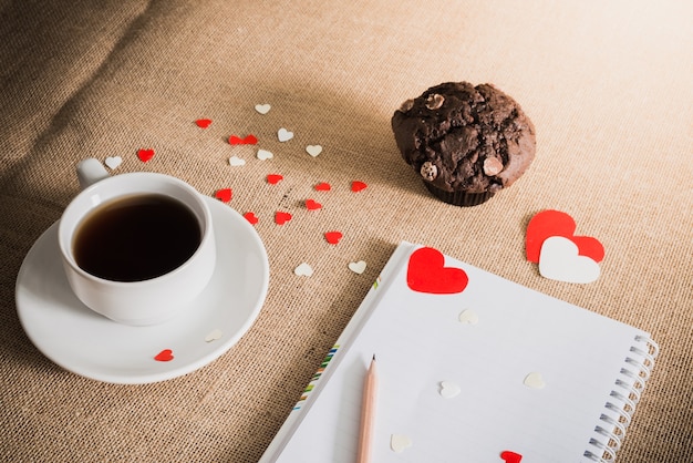 Schokoladenmuffin und Kaffee und Herzen auf Sackleinenbeschaffenheiten