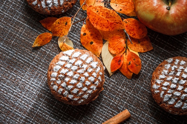 Schokoladenmuffins mit Apfelfüllung auf einem Hintergrund von Herbstblättern und Zimt