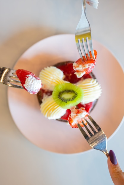 Schokoladenmuffins mit Erdbeeren und weißer Sahne auf Holztisch.